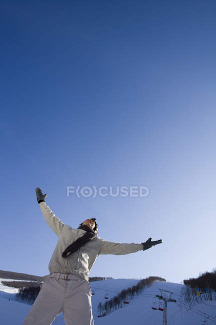 Chinese man with arms outstretched at ski resort — Stock Photo