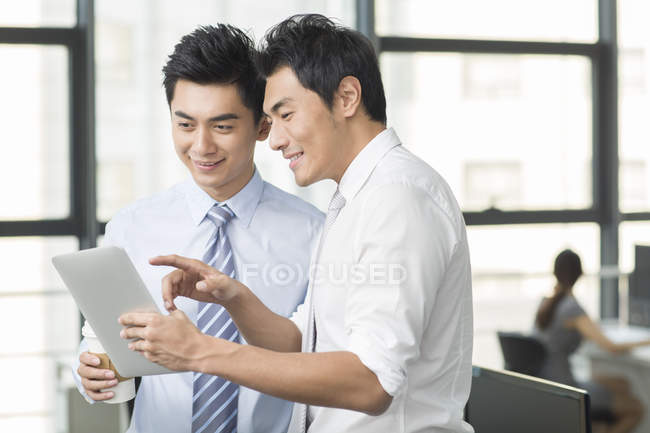 Les hommes d'affaires chinois utilisant une tablette numérique au bureau — Photo de stock