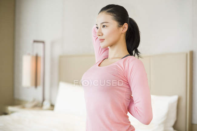 Chinesin in rosa Sportbekleidung dehnt sich im Schlafzimmer — Stockfoto