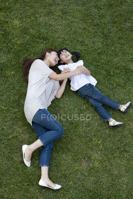 Chinese mother and daughter having fun on green grass — Stock Photo