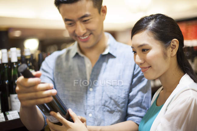 Chinese couple buying wine in supermarket — Stock Photo