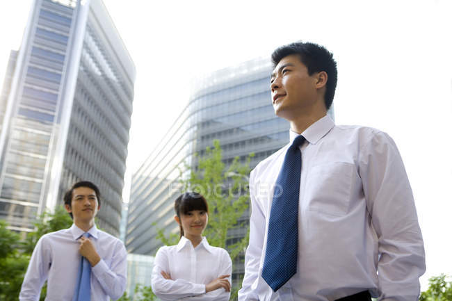 Trabalhadores de escritório chineses em pé na frente de arranha-céus — Fotografia de Stock