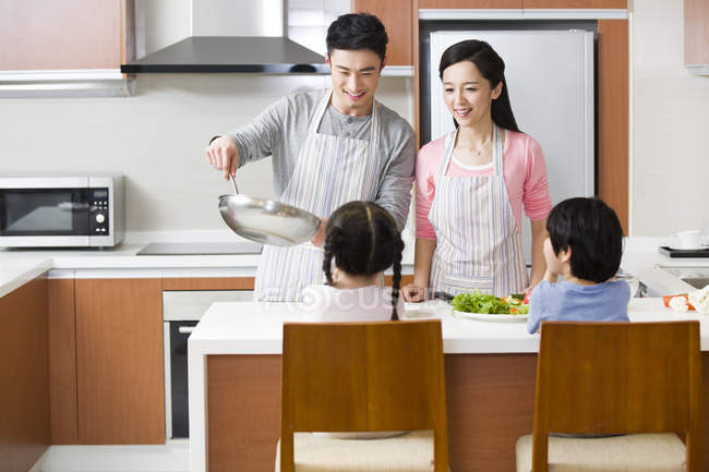 Padres chinos cocinando en la cocina con niños - foto de stock