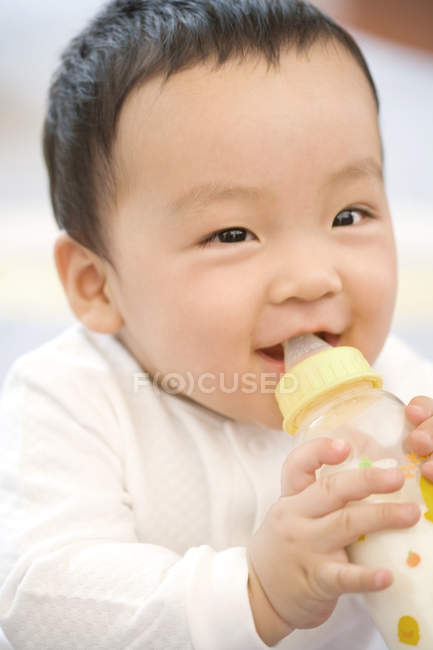 Retrato de bebé chino con biberón de leche - foto de stock