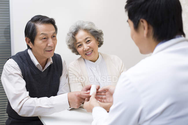 Китайский врач объясняет дозировку лекарств пожилой паре — стоковое фото