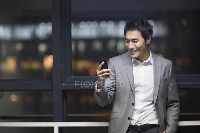 Uomo d'affari cinese utilizzando smartphone in edificio per uffici — Foto stock