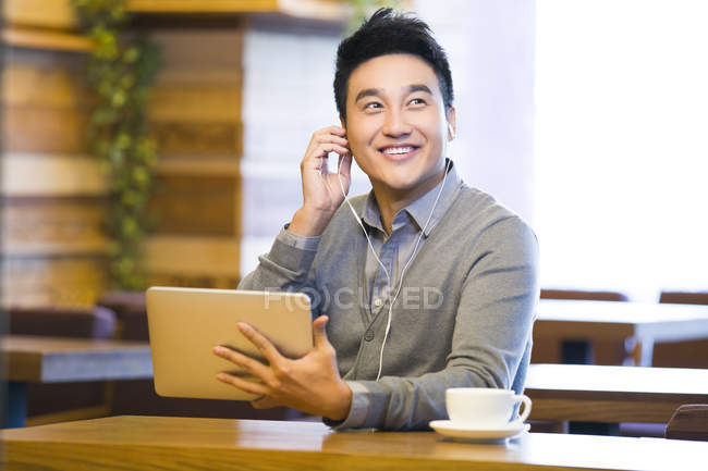 Uomo cinese godendo la musica in tablet digitale in caffetteria — Foto stock