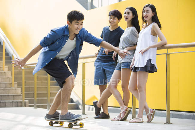 Uomo cinese skateboard con gli amici sulla strada — Foto stock