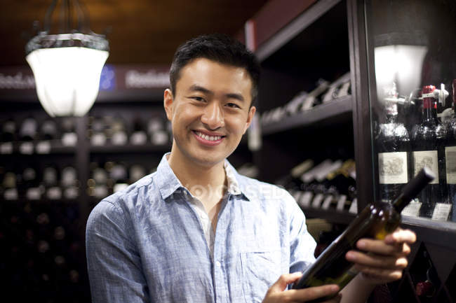 Chinese man choosing wine in cellar — Stock Photo