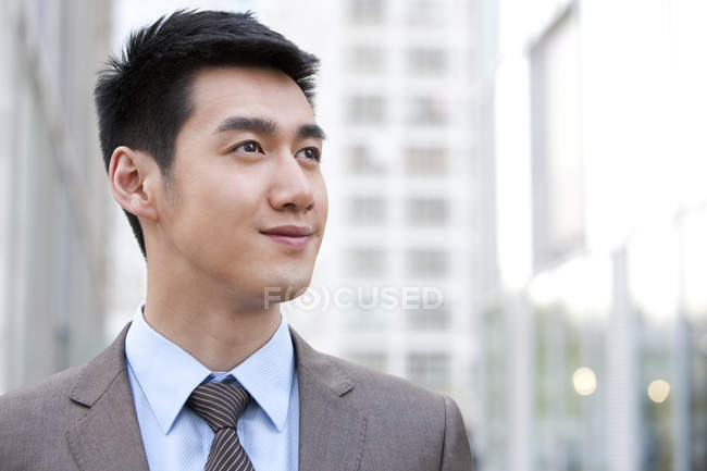 Retrato de jovem empresário chinês olhando para longe na cidade — Fotografia de Stock