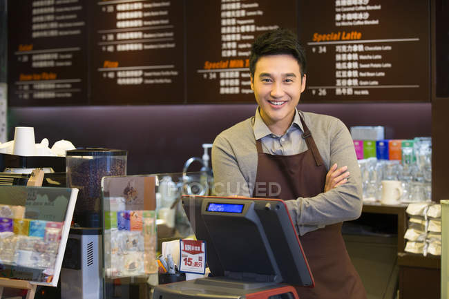 Male Chinese coffee store clerk with arms crossed — Stock Photo