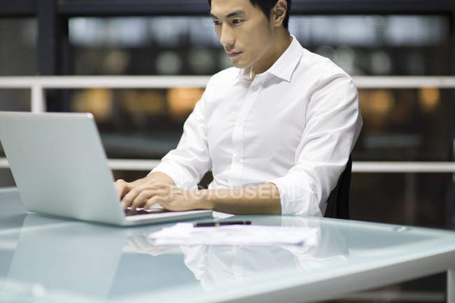Hombre de negocios chino trabajando con portátil en la oficina - foto de stock
