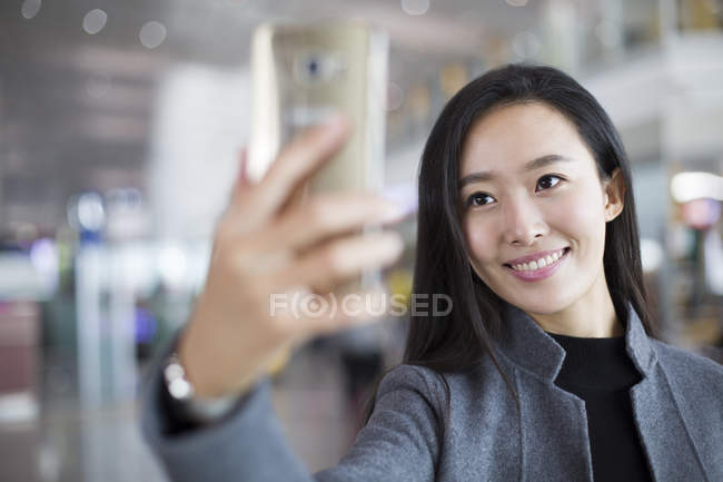 Femme d'affaires chinoise prenant selfie avec smartphone à l'aéroport — Photo de stock