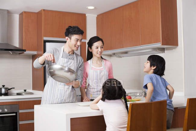Chinese parents cooking in kitchen with children — Stock Photo