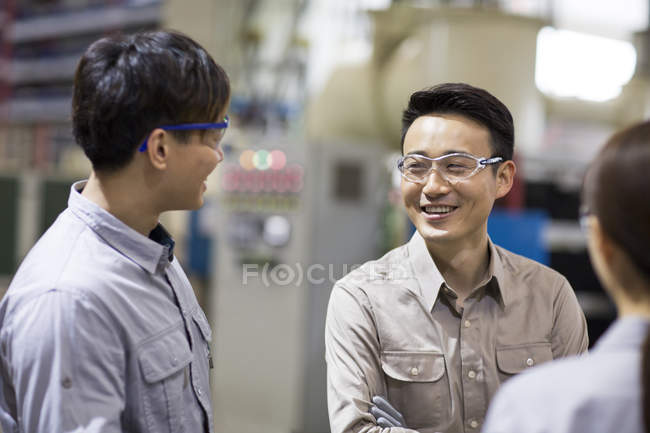 Confident Chinese engineers talking at industrial factory — Stock Photo
