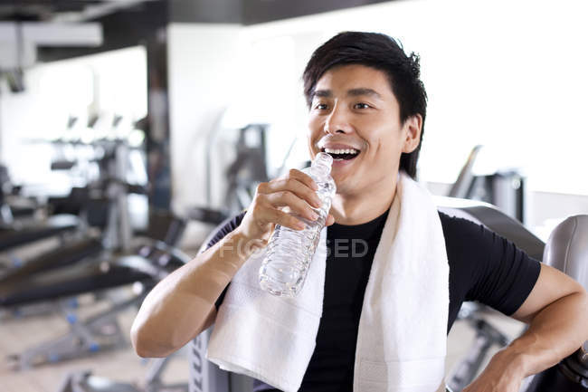 Chinese man drinking water at gym — Stock Photo