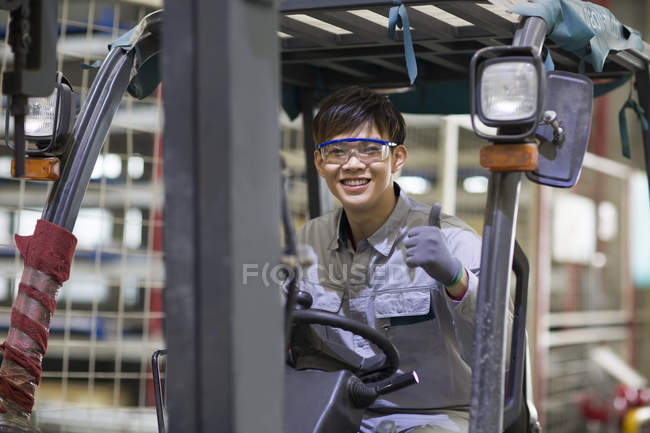 Chinese male worker driving forklift in industrial factory — Stock Photo
