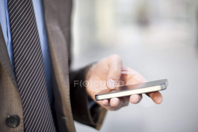 Primer plano del hombre de negocios utilizando el teléfono inteligente en la calle - foto de stock