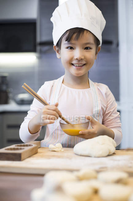 Chinese girl beating egg in home kitchen — Stock Photo