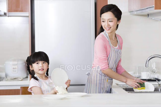 Mãe chinesa e filha lavar pratos na cozinha — Fotografia de Stock