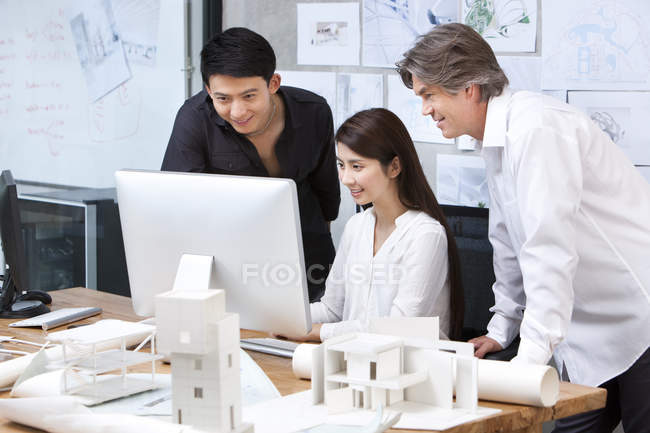 Mature man and chinese architects working with computer — Stock Photo