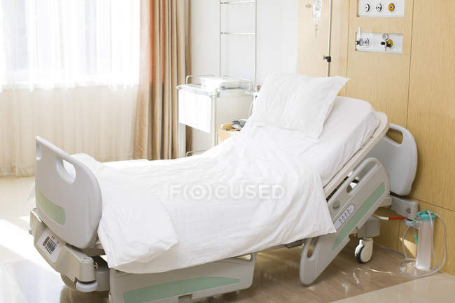 Cama de hospital vacía en la sala de la clínica - foto de stock