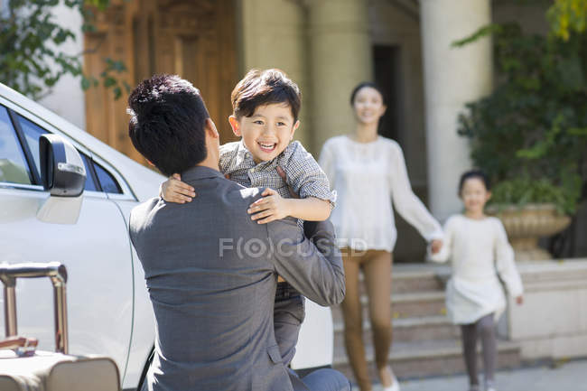 Padre chino sosteniendo y abrazando al hijo en la calle - foto de stock