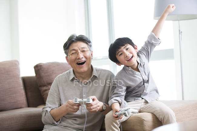 Chinese grandfather and grandson playing video game together — Stock Photo