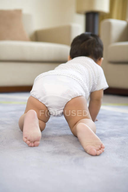 Китайська baby boy повзати по підлозі у вітальні, заднього виду — стокове фото