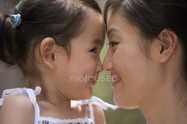 Madre e hija chinas frotando narices, primer plano - foto de stock