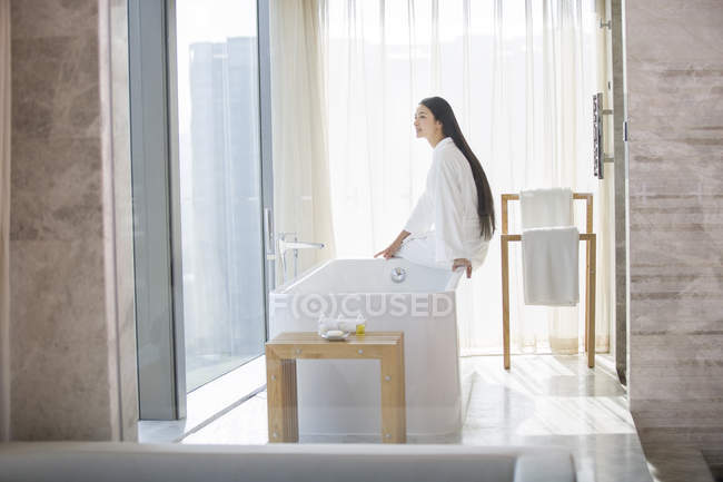 Chinese woman sitting in bathroom — Stock Photo