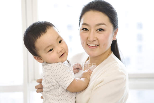 Mujer china sosteniendo bebé niño en las manos - foto de stock