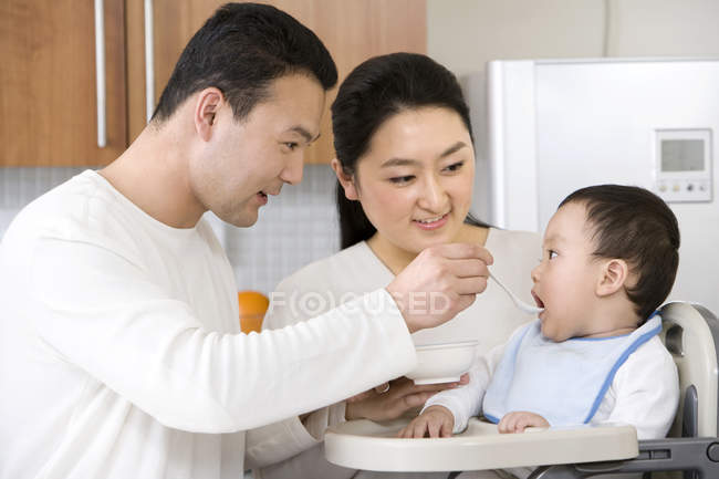 Китайские родители кормят мальчика в детском кресле — стоковое фото