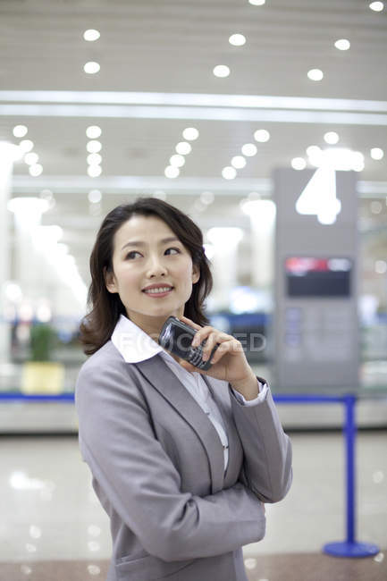 Empresaria china sosteniendo smartphone en aeropuerto - foto de stock
