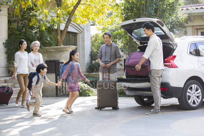 Китайская семья из нескольких поколений упаковывает вещи для поездки на машине — стоковое фото