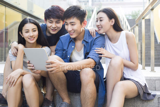 Amigos chineses usando tablet digital e olhando para baixo — Fotografia de Stock