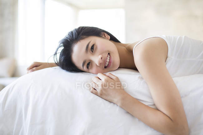 Chinese woman lying on bed and smiling — Stock Photo