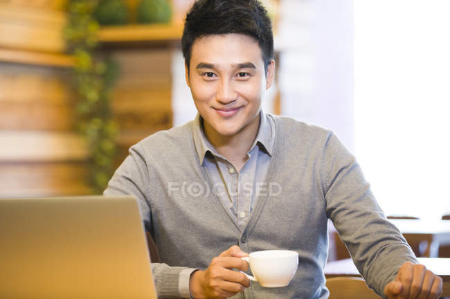 Китайський чоловік тримає чашку кави у кав'ярні — стокове фото
