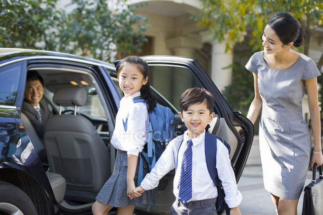 Chinese mother opening car door for children — Stock Photo