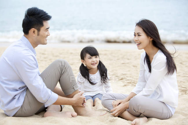 Familia china descansando en la playa de arena - foto de stock