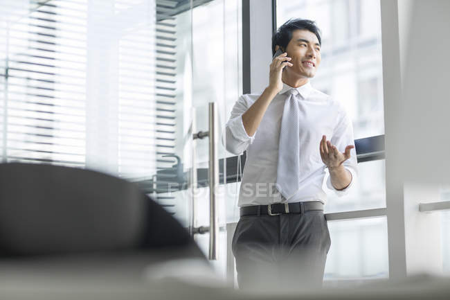 Uomo d'affari cinese che parla al telefono in ufficio — Foto stock