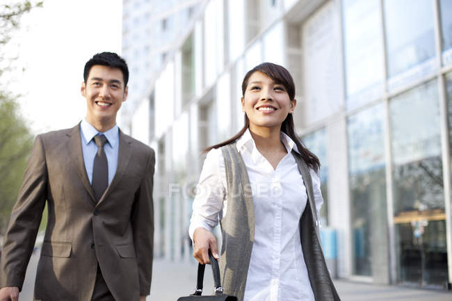 Confident Chinese business people walking with briefcase in city downtown — Stock Photo