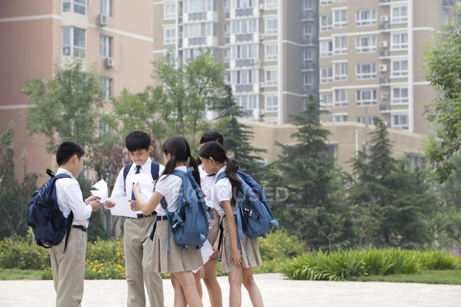 Schoolchildren in school uniform discussing test results at school yard — Stock Photo