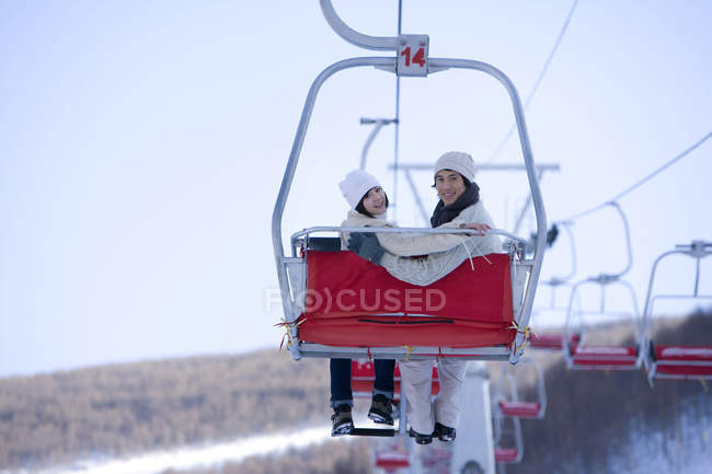 Chinese couple using ski lift at winter resort — Stock Photo