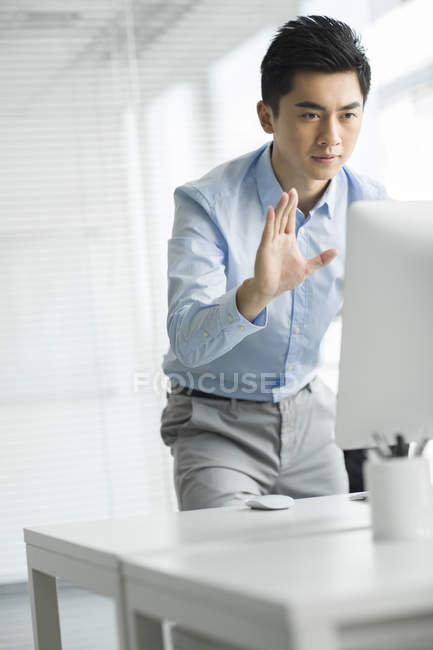 Empresário chinês acenando e olhando para monitor de computador no escritório — Fotografia de Stock