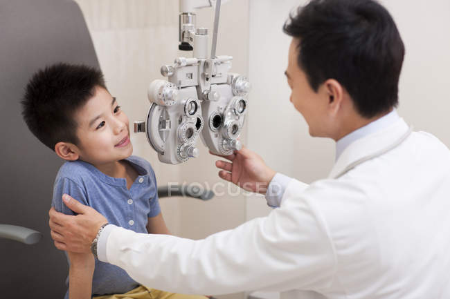 Chino chico recibir ojo examen con foropter - foto de stock