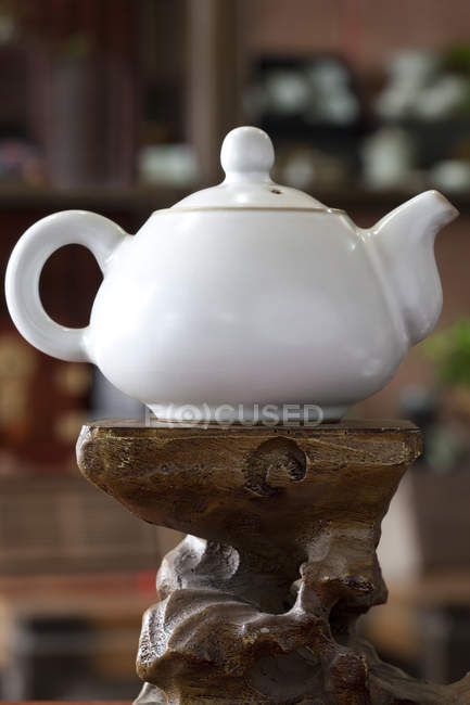 Weiße Teekanne auf Wurzelschnitzen — Stockfoto