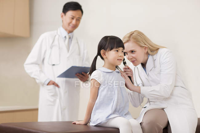 Doctors examining girl ear in hospital — Stock Photo