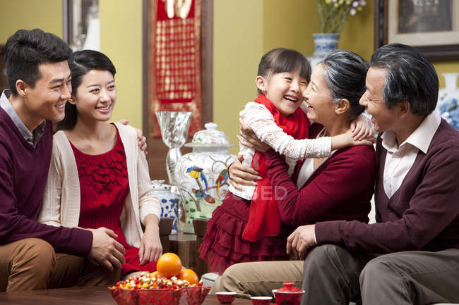 Девушка обнимает бабушку во время китайского Нового года с семьей — стоковое фото
