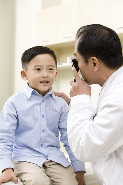Chinês maduro médico examinando menino no hospital — Fotografia de Stock